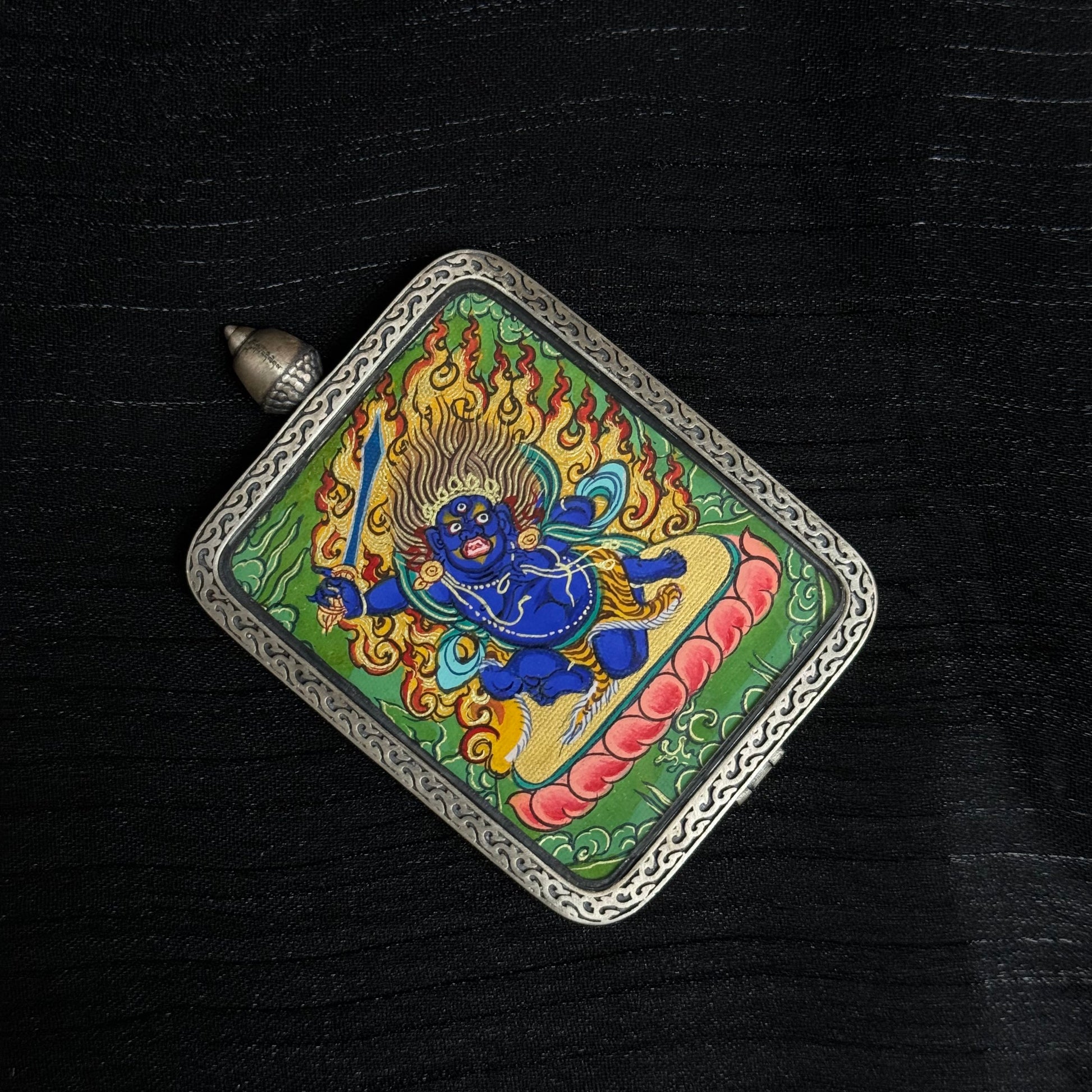 The Rekong Cuiying Acala Thangka pendant displayed as a sacred amulet for awakening and protection, embodying Buddhist tradition.
