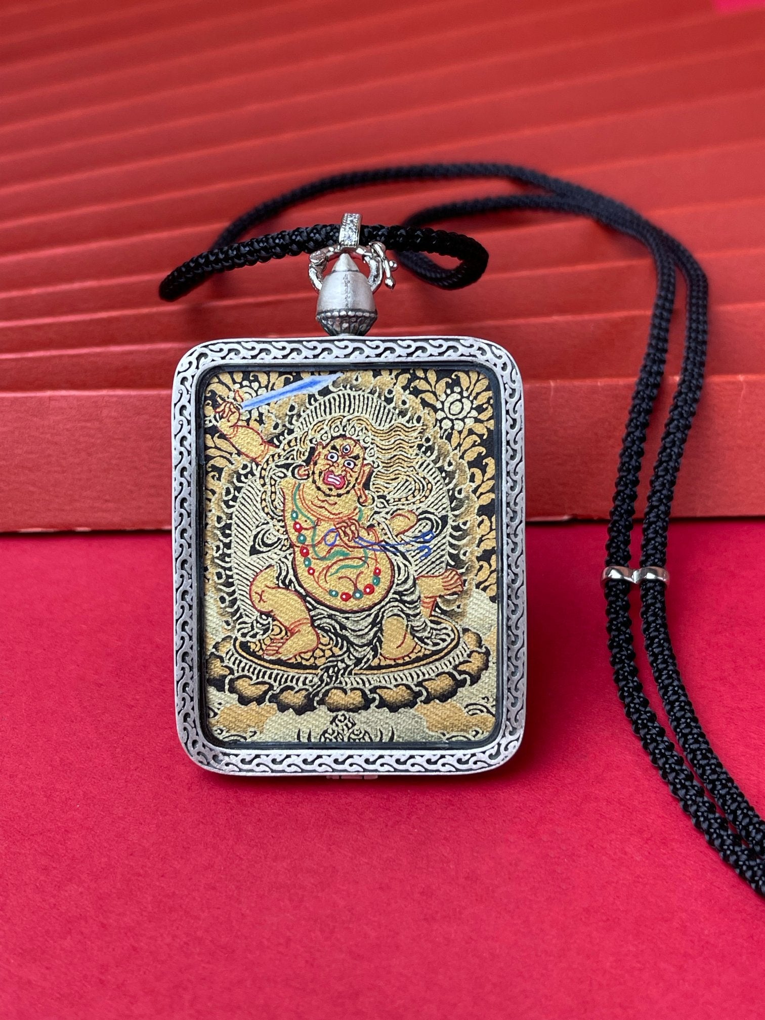 The Rekong Black Gold Acala Thangka pendant with deer relief silver casing displayed as a sacred amulet for steadfast will and clear obstacles, embodying Buddhist tradition.


