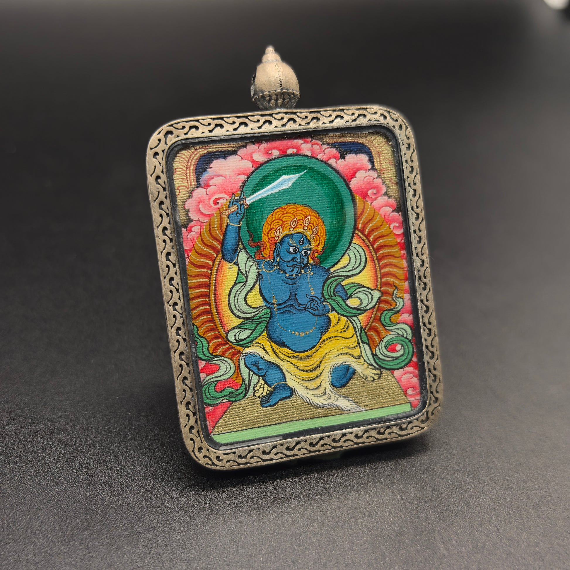  A 3.5x4.5cm hand-painted Tibet Red Cloud Acala (不动明王) Thangka pendant with 925 silver featuring the Immovable One, chief of the five wisdom kings, representing discipline and protection in Buddhist tradition.
