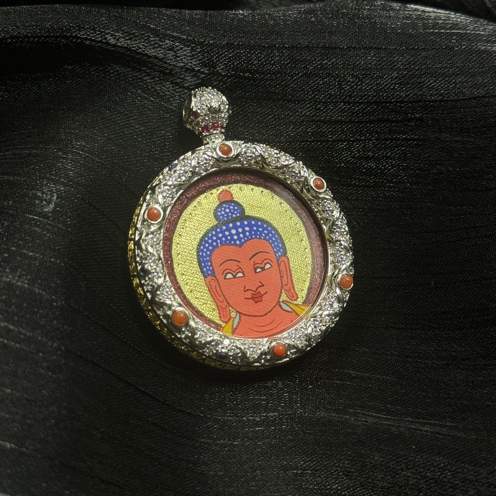 The Rekong Red-Gold Amitabha Buddha Head Thangka pendant displayed as a sacred amulet for liberation and pure-land aspiration, embodying Buddhist tradition.
