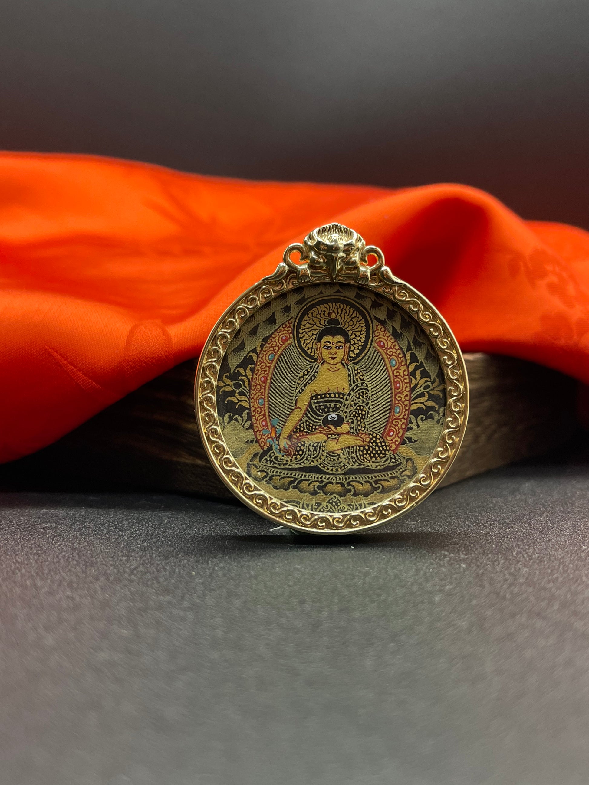  A 3.5cm hand-painted Rekong Black Gold Bhaisajyaguru (药师佛) Thangka pendant with copper casing featuring the Medicine Buddha, lord of the Eastern Lapis Lazuli Pure Land, representing healing and longevity in Buddhist tradition.
