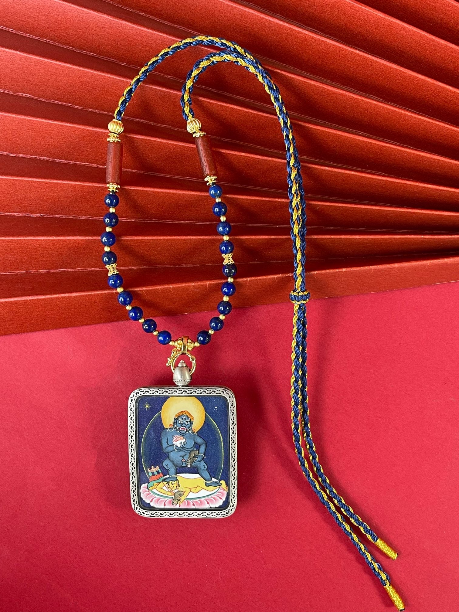 The Tibet Black Jambhala Thangka pendant with copper casing displayed as a sacred amulet for instant bestowal of wealth and relief from poverty, embodying Buddhist tradition.
