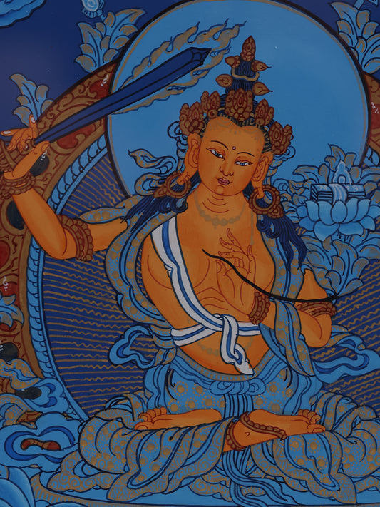 Blue-ground Tibetan thangka of Manjushri holding the flaming sword of wisdom and sacred scripture.