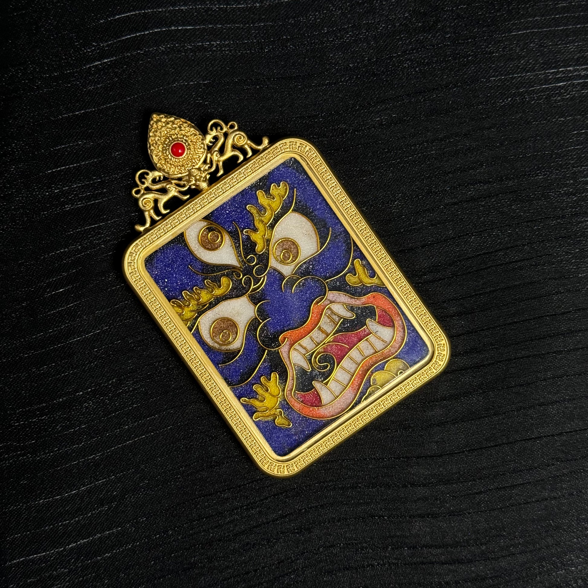The cloisonné Mahakala Thangka pendant displayed as a sacred amulet for protection and fortune.
