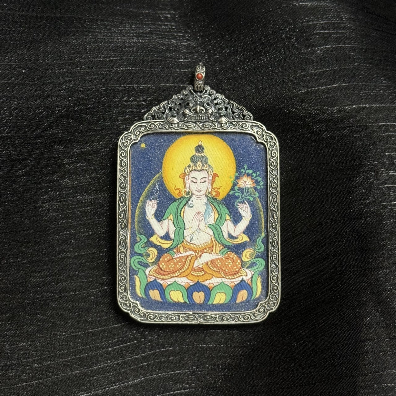  Detailed view of the antique silver-tone casing for the Four-Armed Avalokiteshvara Thangka pendant, symbolising protection and elegance in Tibetan Buddhist tradition.

