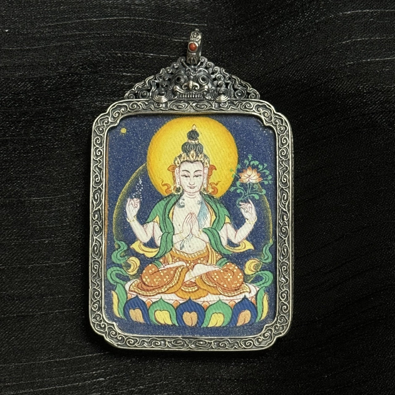  The Bold Four-Armed Avalokiteshvara Thangka pendant displayed as a sacred amulet for compassion and family peace, embodying the great compassion of Tibetan Buddhist tradition.

