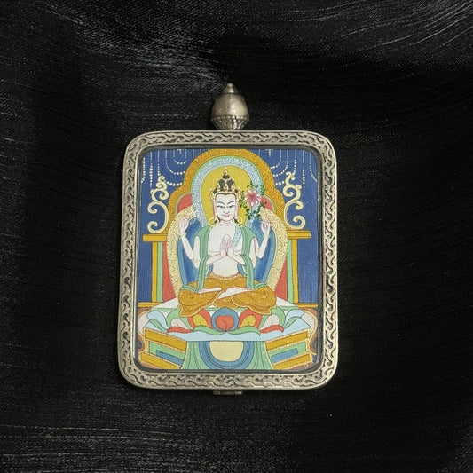 The Karma Kagyu Four-Armed Avalokiteshvara Thangka pendant displayed as a sacred amulet for compassion and peace, embodying Tibetan Buddhist tradition.