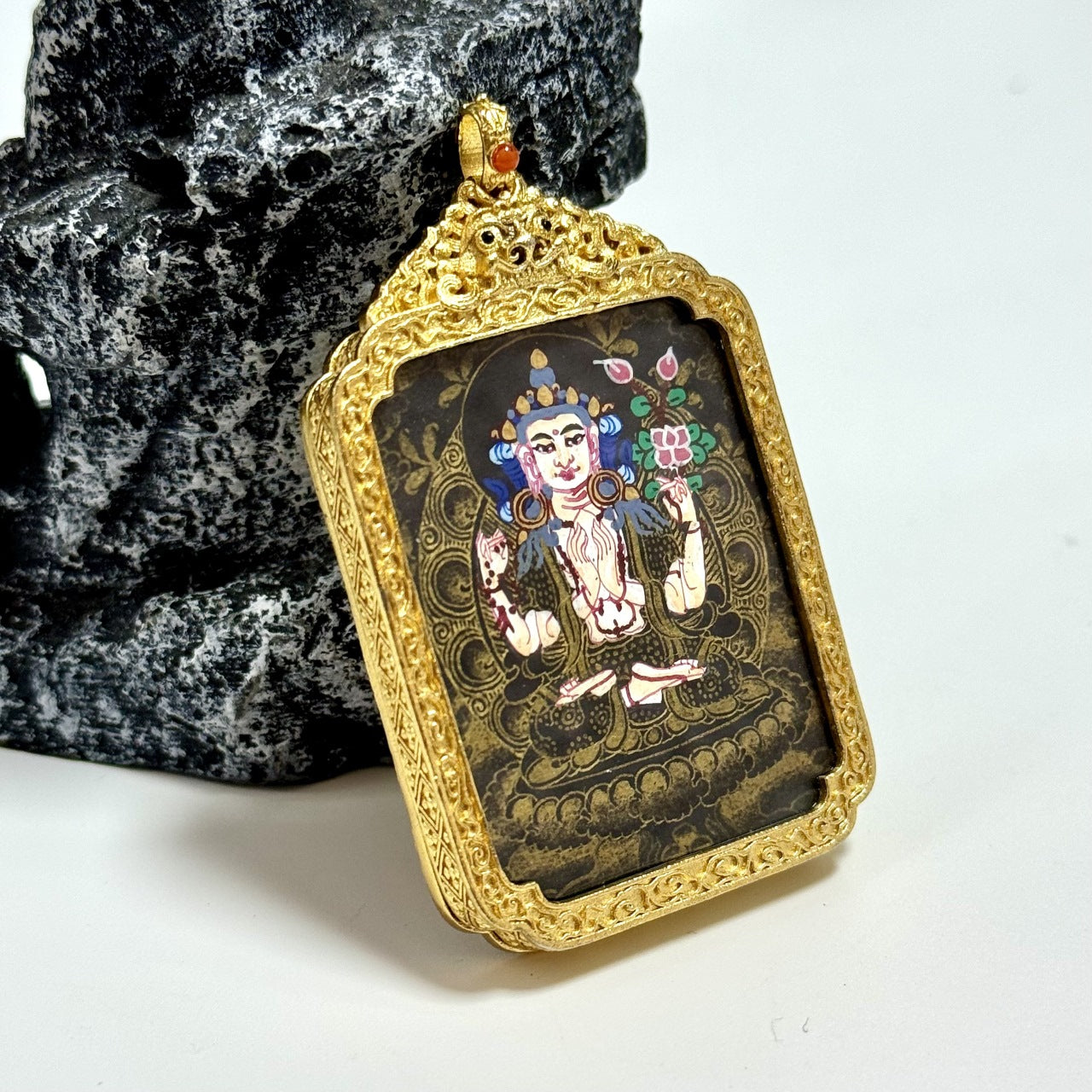 The Nepal Black Gold Four-Armed Avalokiteshvara Thangka pendant displayed as a sacred amulet for compassion and peace, embodying Tibetan Buddhist tradition.
