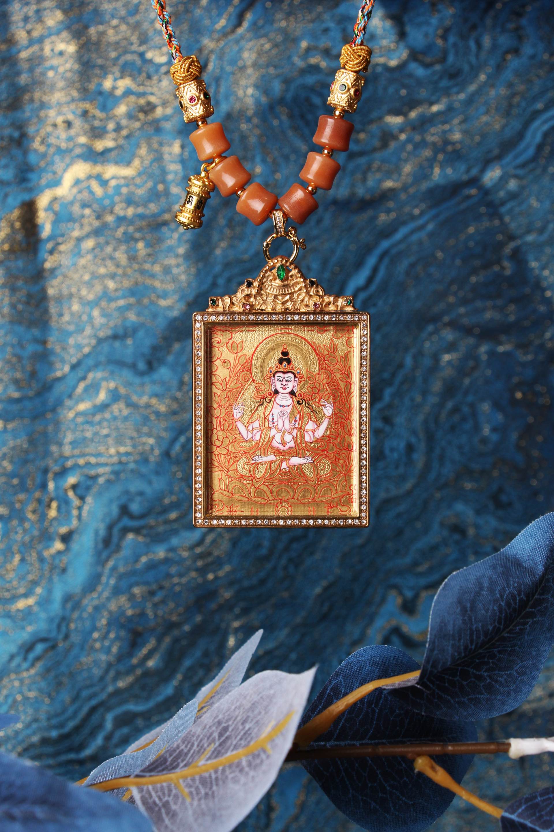 The Rebgong Four-Armed Avalokiteshvara Thangka pendant displayed as a sacred amulet for compassion and healing, embodying the mercy of Tibetan Buddhist tradition.

