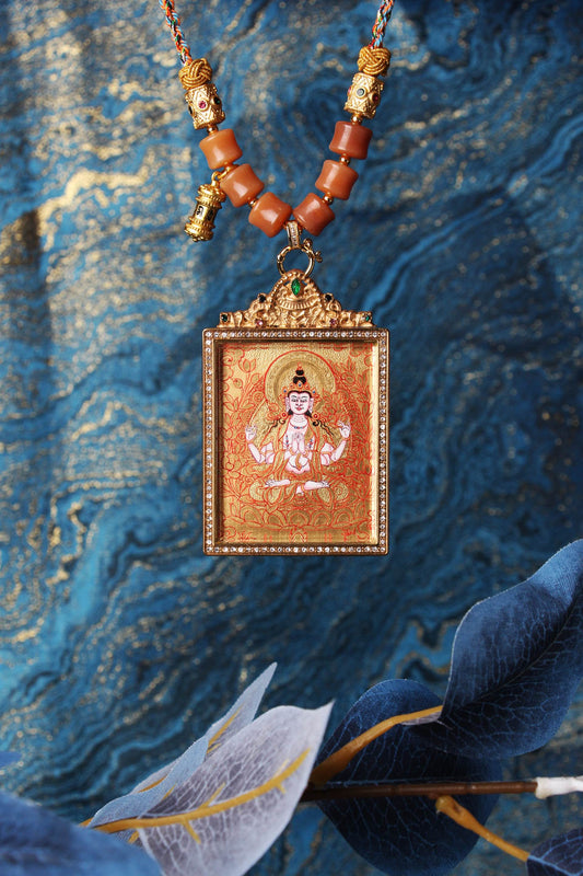 The Rebgong Four-Armed Avalokiteshvara Thangka pendant displayed as a sacred amulet for compassion and healing, embodying the mercy of Tibetan Buddhist tradition.

