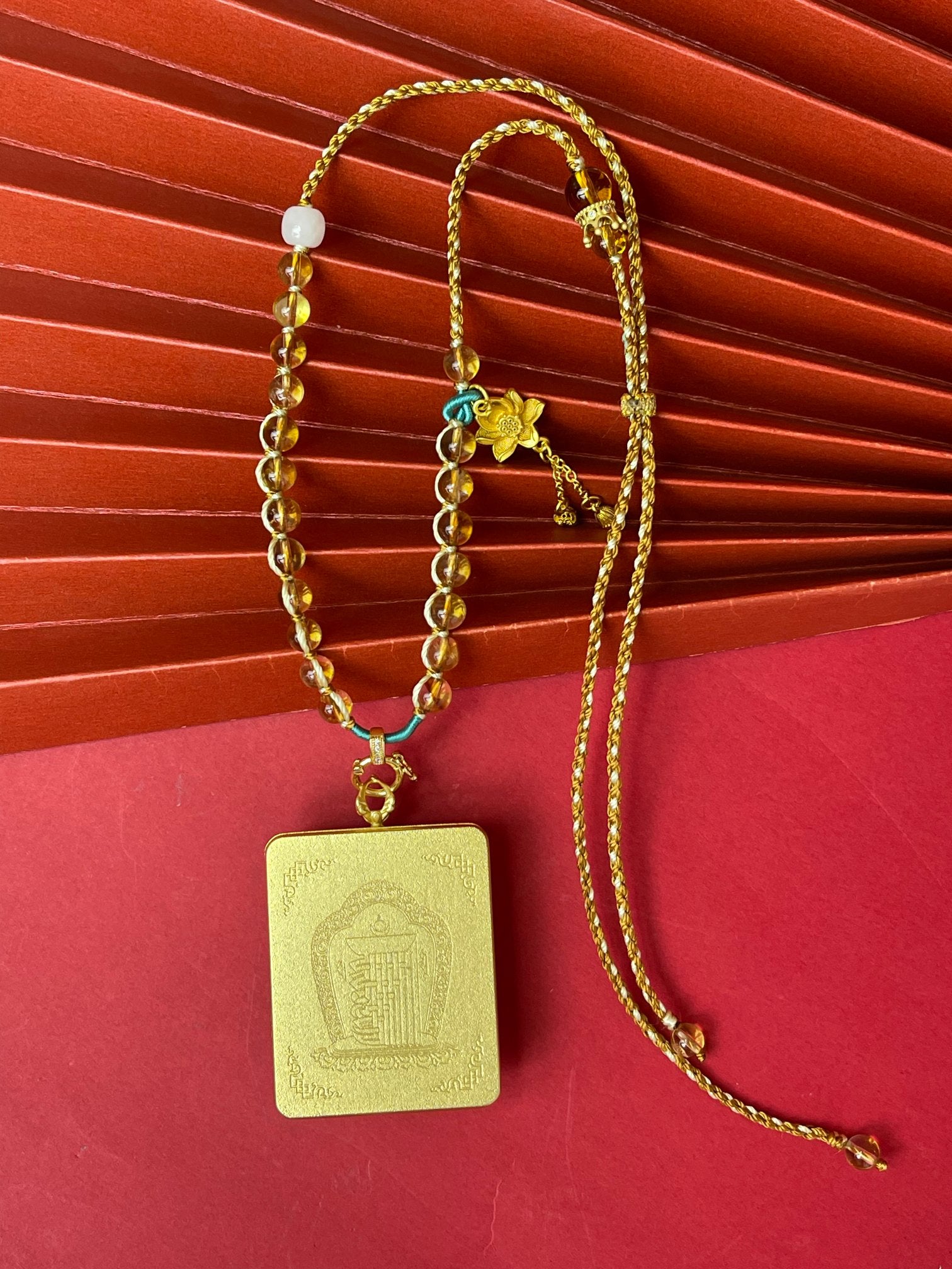  The Rekong Four-Armed Avalokiteshvara Thangka pendant with hand-woven cord displayed as a sacred amulet for compassion and family harmony, embodying Buddhist tradition.
