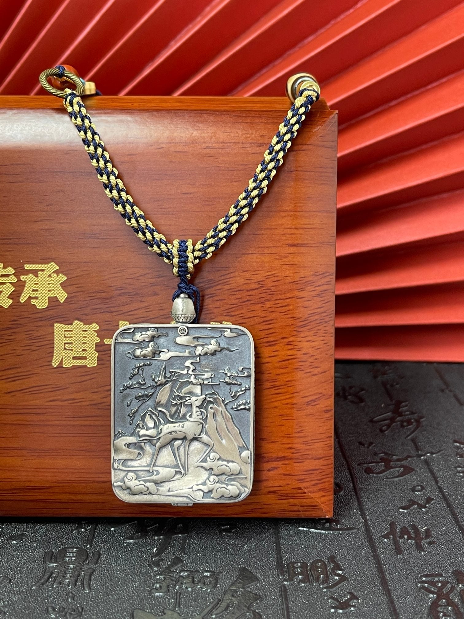  The Rekong Four-Armed Avalokiteshvara Thangka pendant with hand-woven cord displayed as a sacred amulet for compassion and family harmony, embodying Buddhist tradition.
