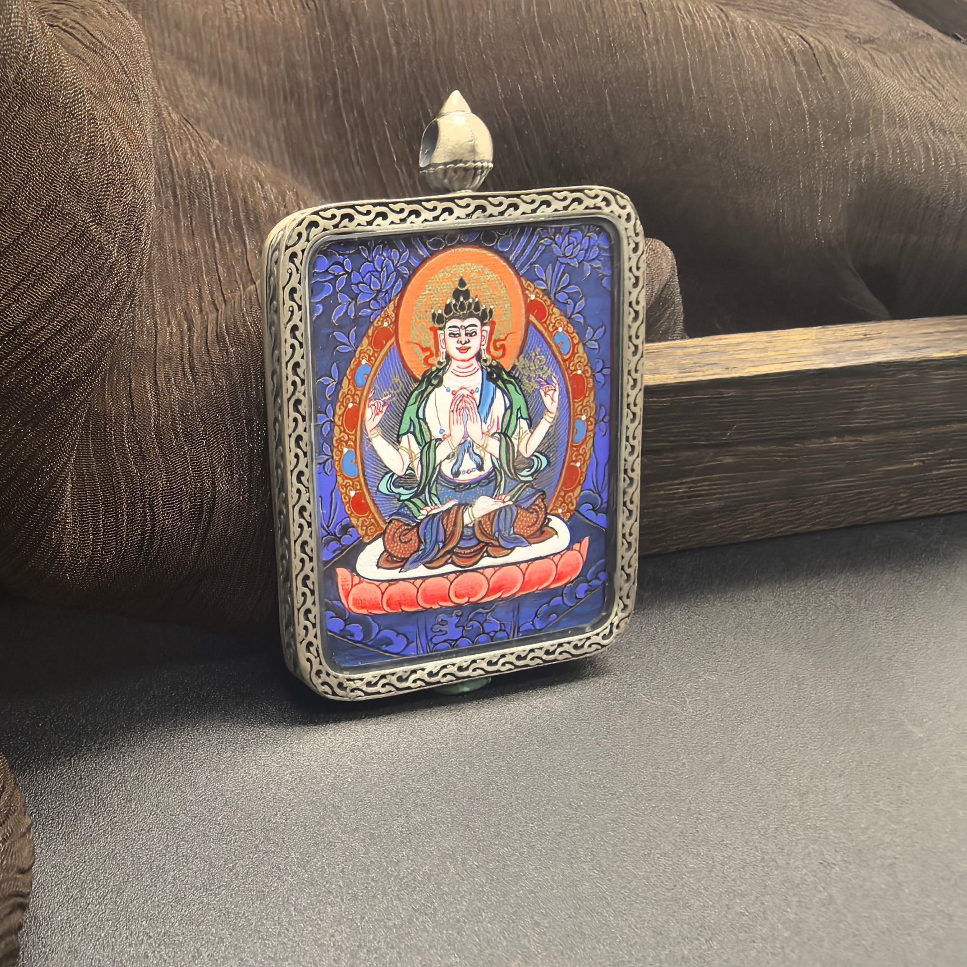The Rekong Blue Thangka Four-Armed Avalokiteshvara Thangka pendant with 925 silver displayed as a sacred amulet for compassion and peace, embodying Buddhist tradition.


