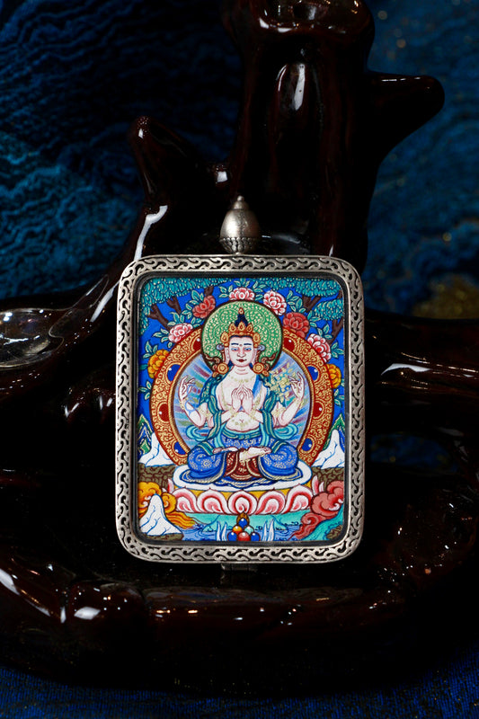 A sacred hand-painted Four-Armed Avalokiteshvara Thangka pendant from Regong, featuring the Bodhisattva of Compassion in a fine silver frame.
