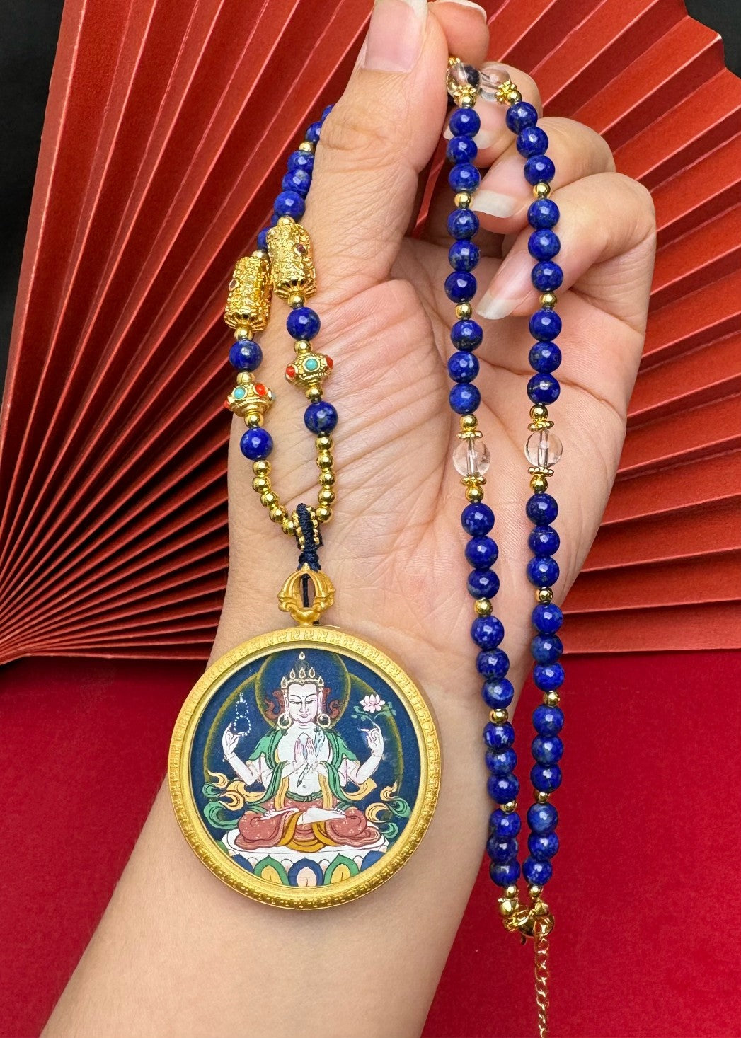 The Tibet Bold Four-Armed Avalokiteshvara Thangka pendant with copper casing displayed as a sacred amulet for compassion and protection, embodying Buddhist tradition.
