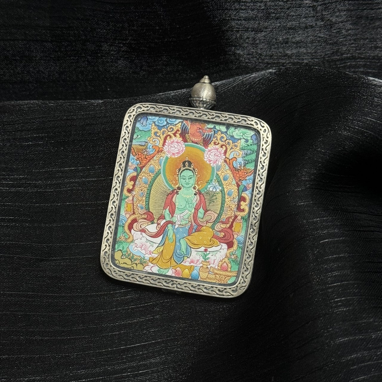 A 4x5cm hand-painted Menri-style Green Tara Thangka pendant featuring the Liberator from Eight Fears, encased in 925 silver with Dunhuang Nine-Colour Deer design, symbolising liberation and wisdom in Tibetan Buddhist tradition.

