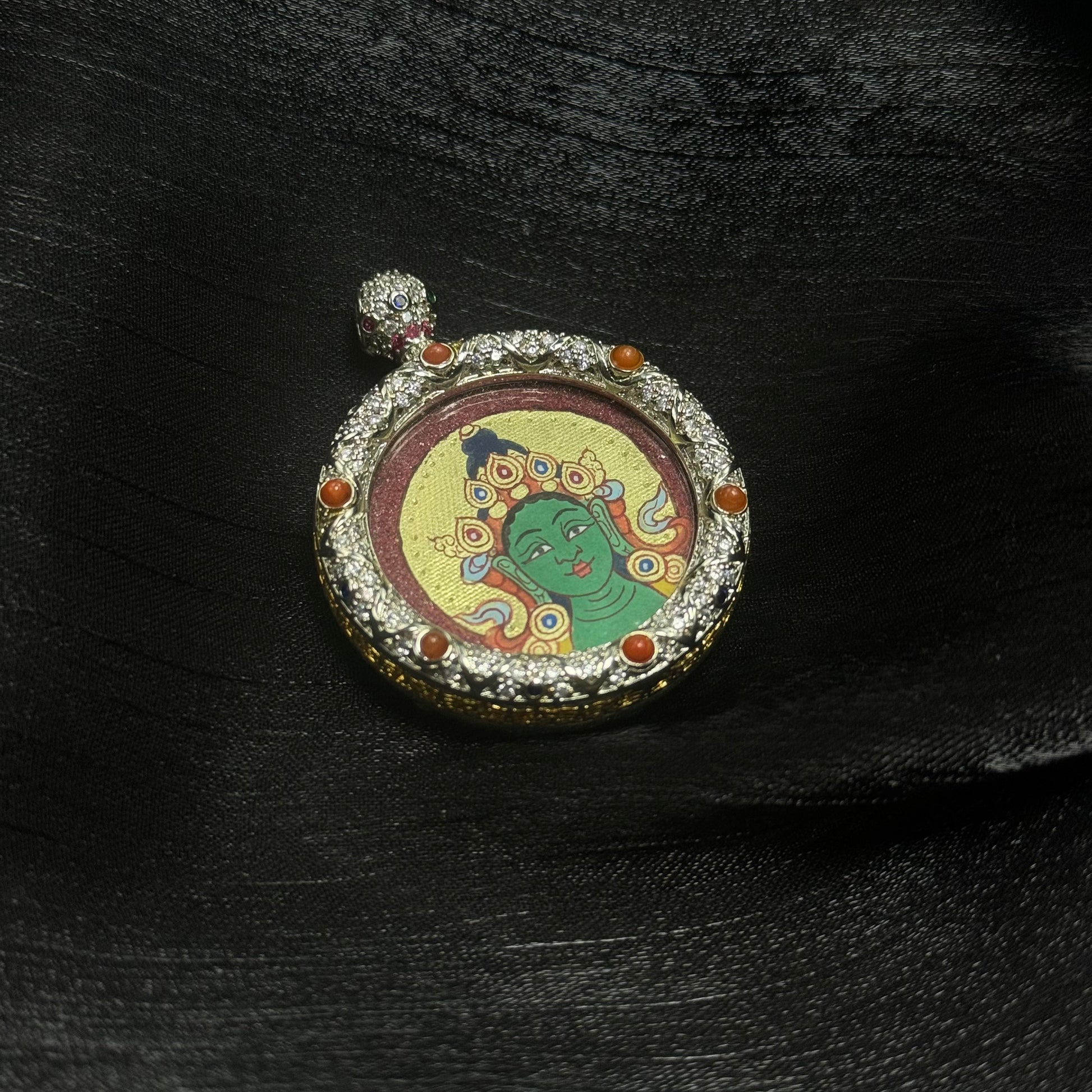  The Rekong Red-Gold Green Tara Buddha Head Thangka pendant displayed as a sacred amulet for liberation and protection, embodying Buddhist tradition.