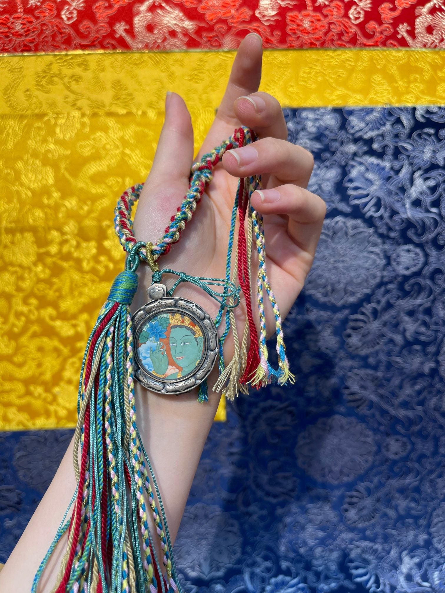  The Tibet Card Green Tara 2.5cm pendant with hand-woven cord displayed as an amulet for wisdom, merit and love.
