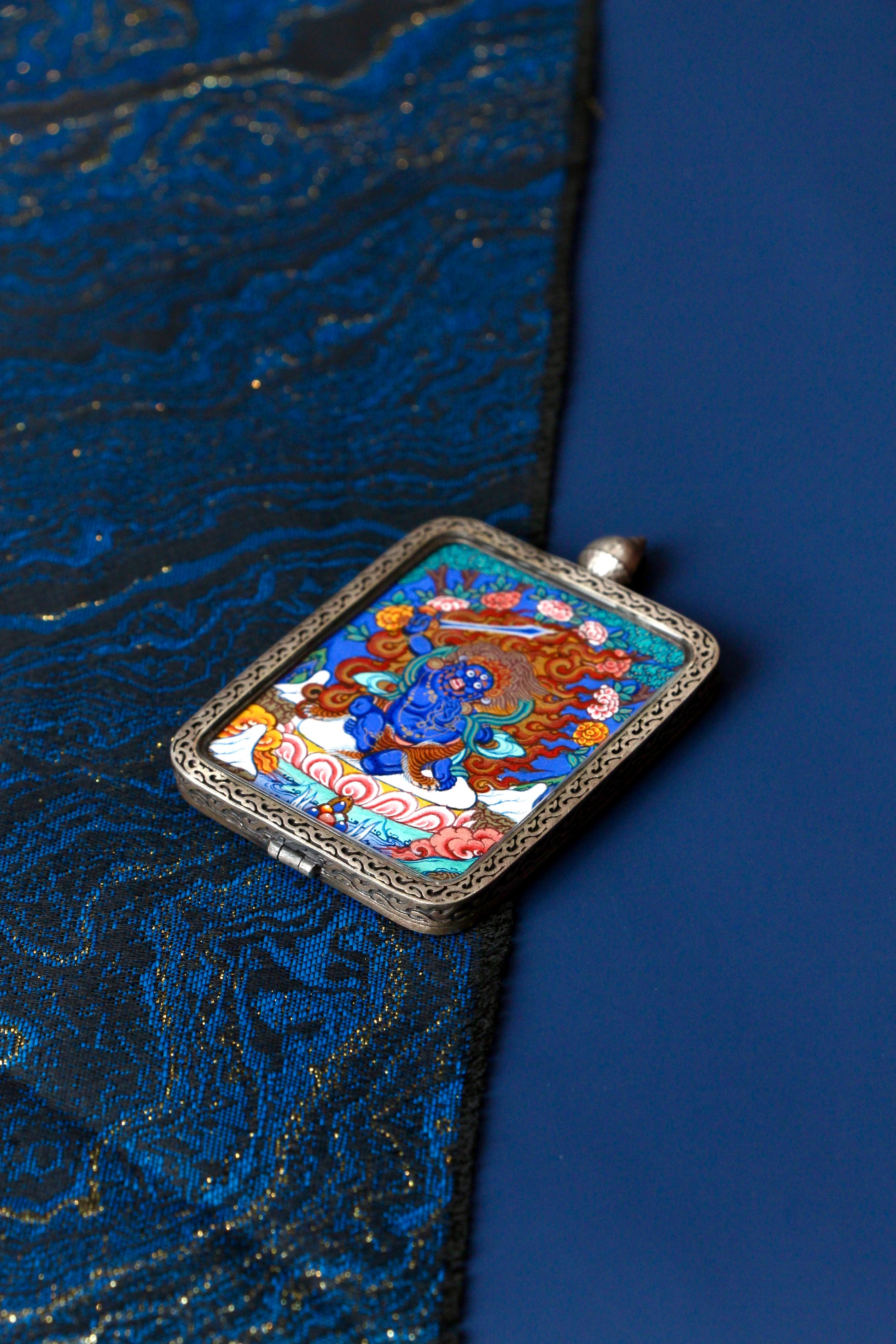 Macro view of a miniature Acala Thangka showing the fiery aura and intense blue pigments used in traditional Regong artistry.