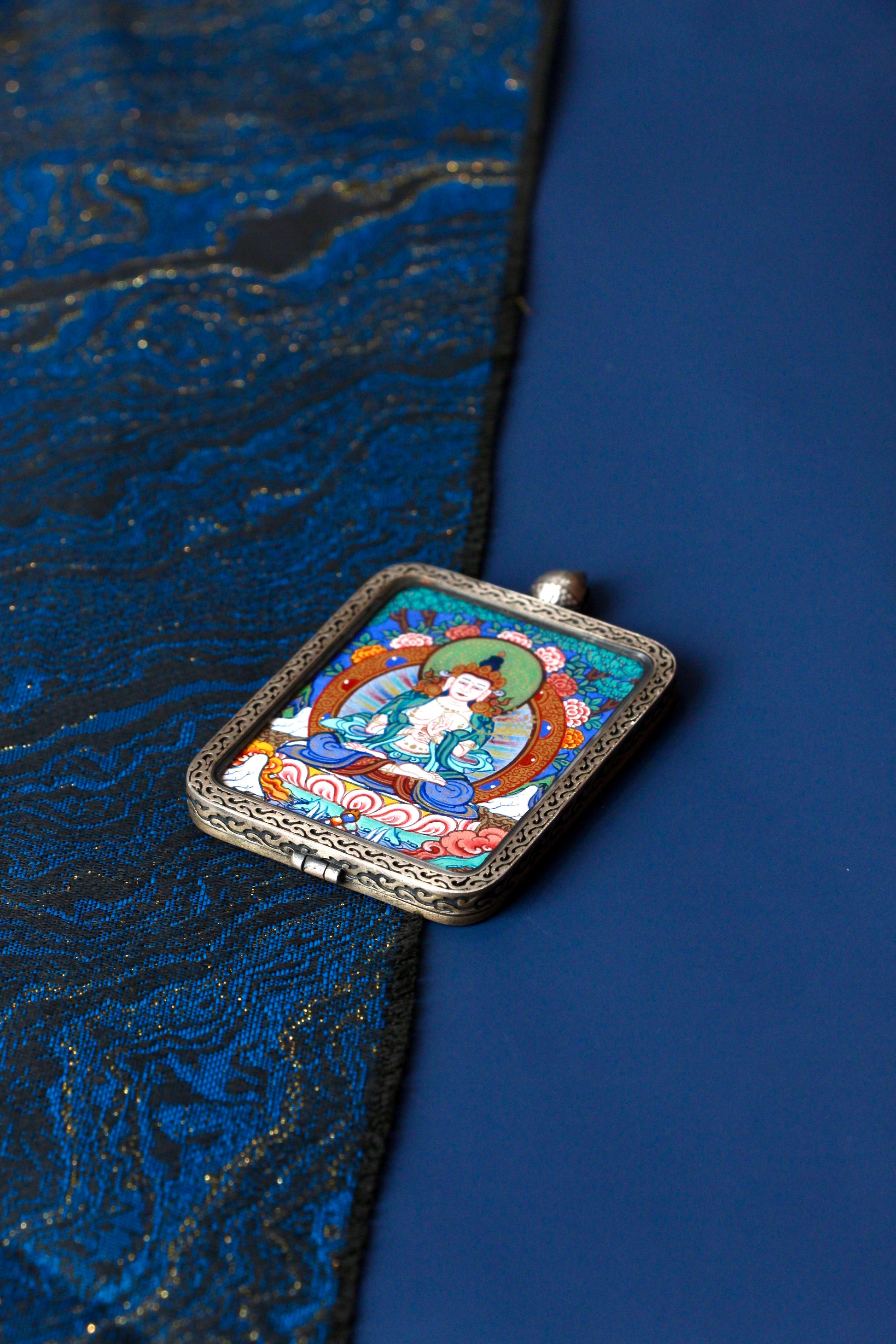 Macro view of a miniature Mahasthamaprapta Thangka showing the delicate brushwork and natural mineral colors used in traditional Regong artistry.