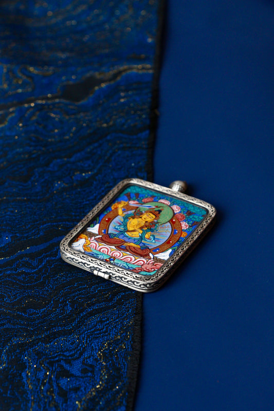 Macro view of a miniature Manjushri Thangka showing the precise golden detailing and natural mineral colors used in traditional Regong artistry.