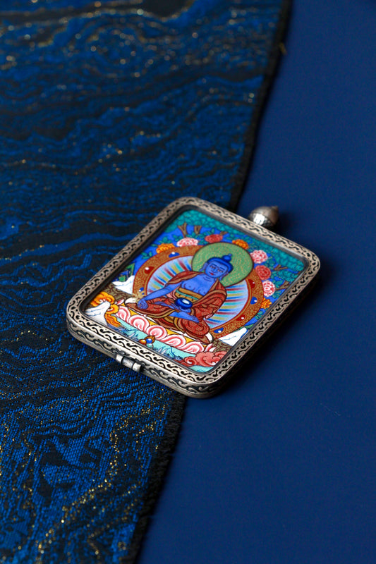 Macro view of a miniature Medicine Buddha Thangka showing the detailed brushwork and natural mineral pigments used in Regong artistry.