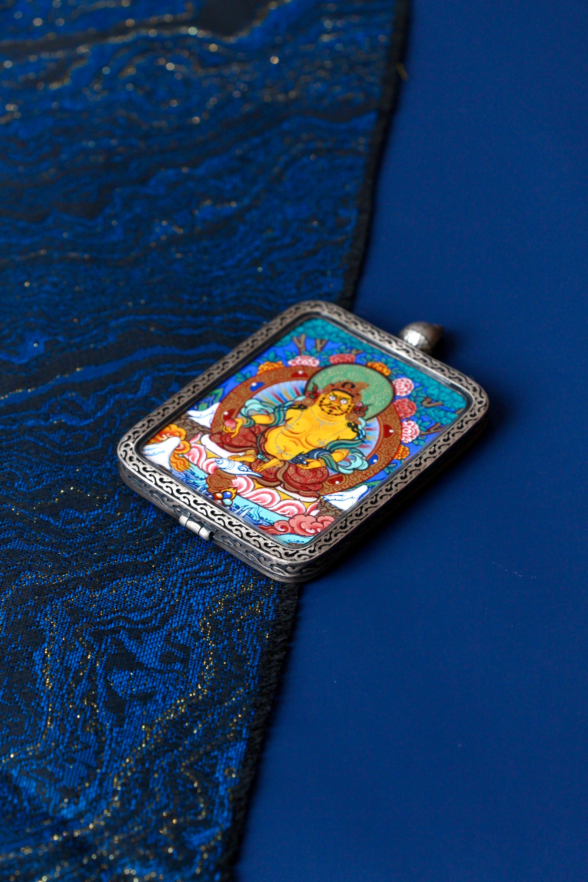 Macro detail of a miniature Zambala Thangka painted with traditional mineral pigments, showing exquisite brushwork and vibrant colors of Himalayan sacred art.