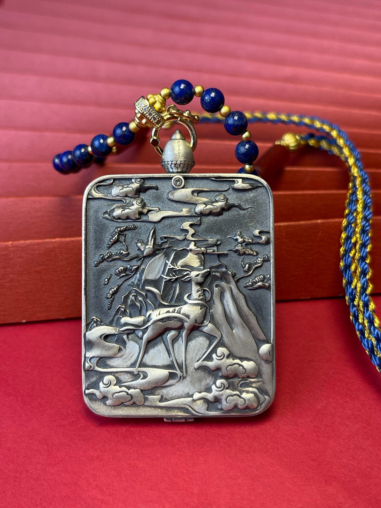 The Rekong Ksitigarbha Thangka pendant with 925 silver casing and lapis cord displayed as a sacred amulet for the great vow and fulfilment of wishes, embodying Buddhist tradition.
