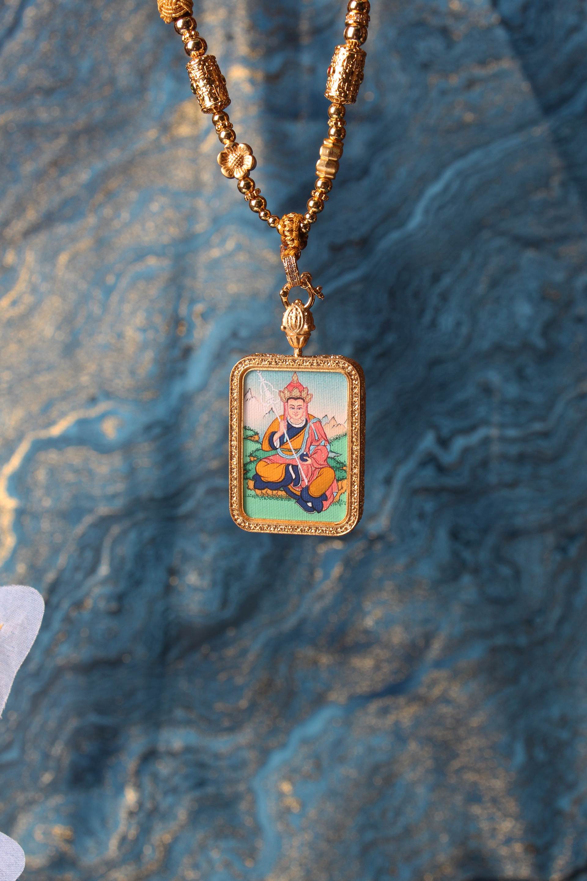The Tibetan Buddhist Ksitigarbha Bodhisattva Thangka pendant displayed as a sacred amulet for liberation and protection, embodying the compassionate vow of Tibetan Buddhist tradition.
