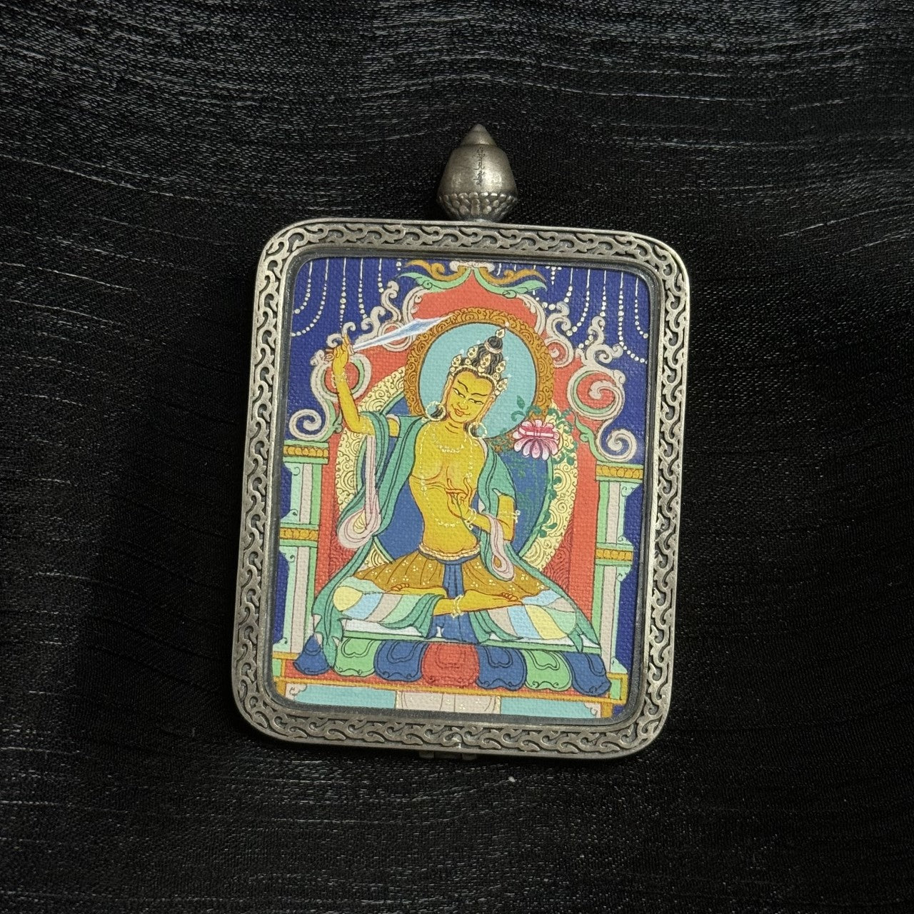  The Karma Kagyu Manjushri Thangka pendant displayed as a sacred amulet for wisdom and success, embodying Tibetan Buddhist tradition.
