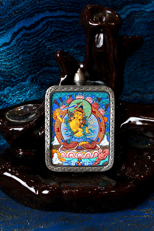 A sacred hand-painted Manjushri Bodhisattva Thangka pendant from Regong, featuring the Bodhisattva of Wisdom with a flaming sword in a fine silver frame.