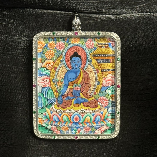 The Medicine Buddha with Mandala Thangka pendant displayed as a sacred amulet for healing, longevity and peace, embodying Tibetan Buddhist tradition.
