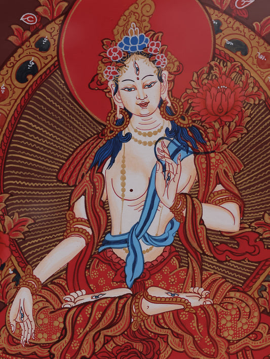White Tara depicted on a red background thangka, representing compassion and spiritual blessings in Tibetan Buddhism