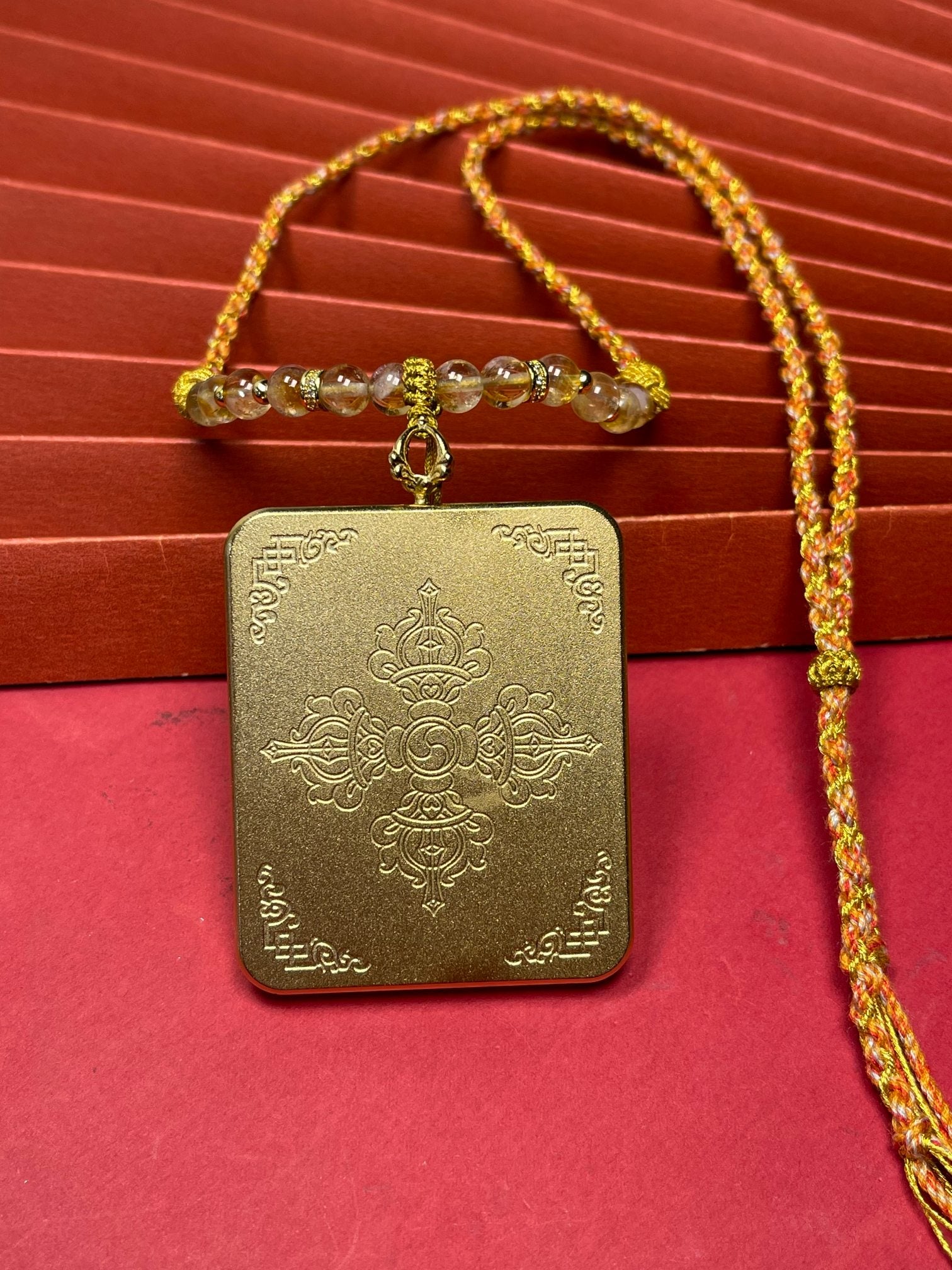 The Nepal Pink Shachilama Thangka pendant with hand-designed cord displayed as a sacred amulet for wealth and peace, embodying Buddhist tradition.
