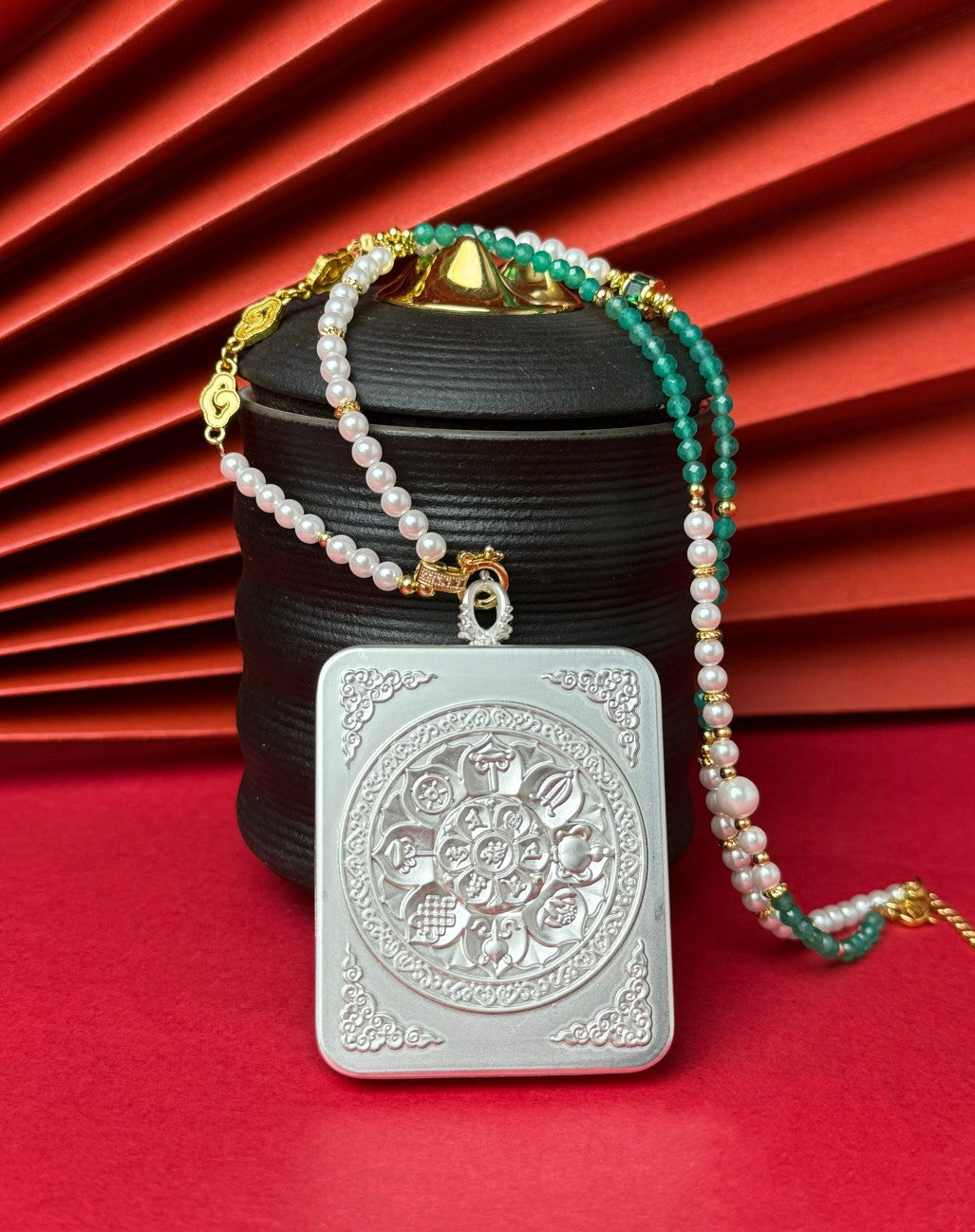 The Nepal Pink Shachilama Past and Present Thangka pendant with hand-designed cord displayed as a sacred amulet for wealth and peace, embodying Buddhist tradition.

