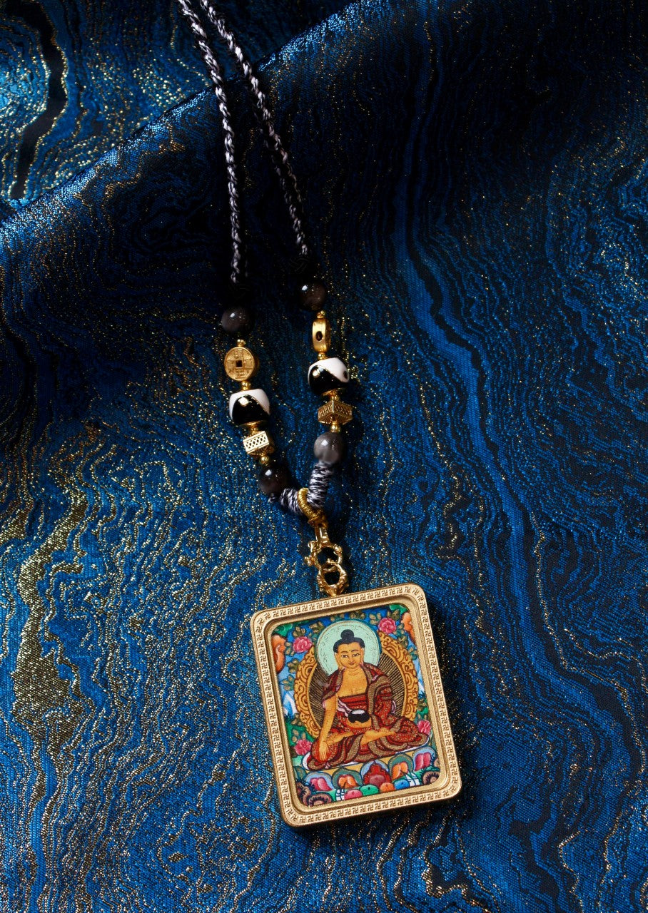 Shakyamuni Buddha thangka pendant depicting the historical Buddha in Tibetan Buddhist culture, symbolizing peace, wisdom, and enlightenment.