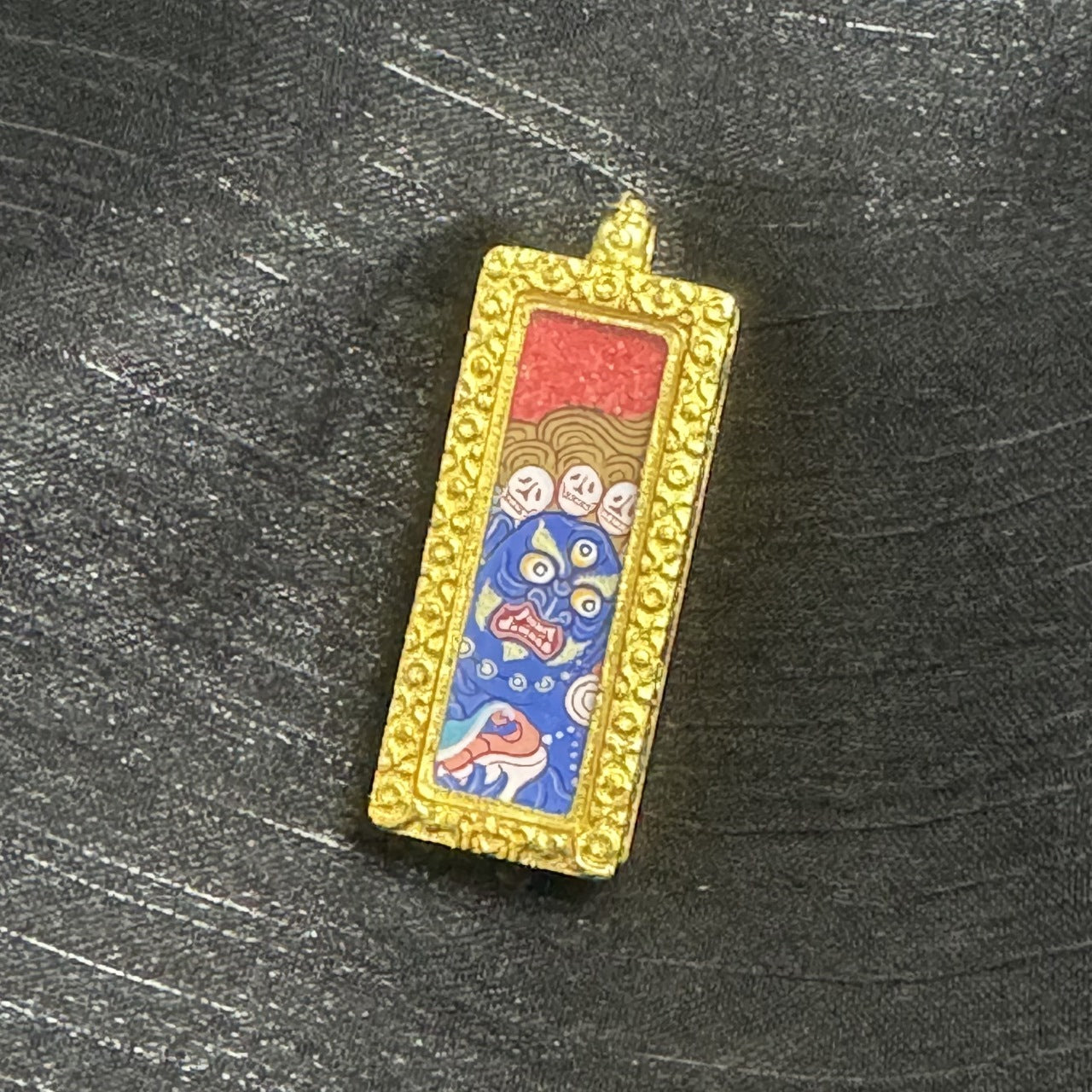  The Rebgong Buddha Head Six-Armed Mahakala Thangka pendant displayed as a sacred amulet for protection and success, embodying Tibetan Buddhist tradition.