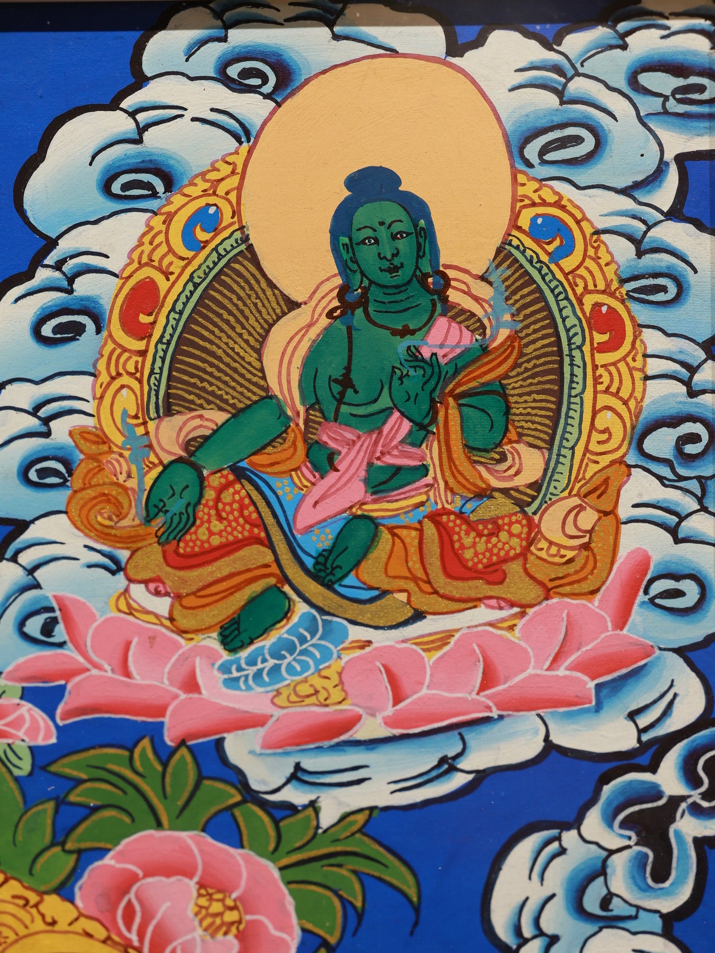 Manjushri thangka with intricate ornamentation, cloud motifs, and prayer flags, reflecting traditional Tibetan Buddhist iconography.