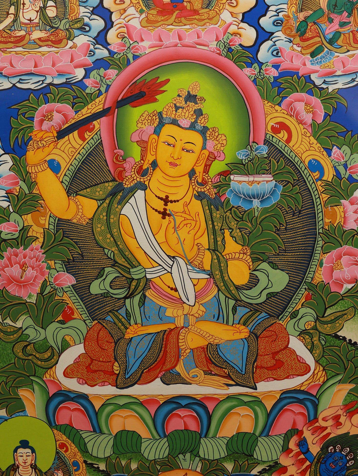 Color thangka depicting Manjushri in youthful form, holding a scripture book and flaming wisdom sword, representing the union of knowledge and enlightenment.