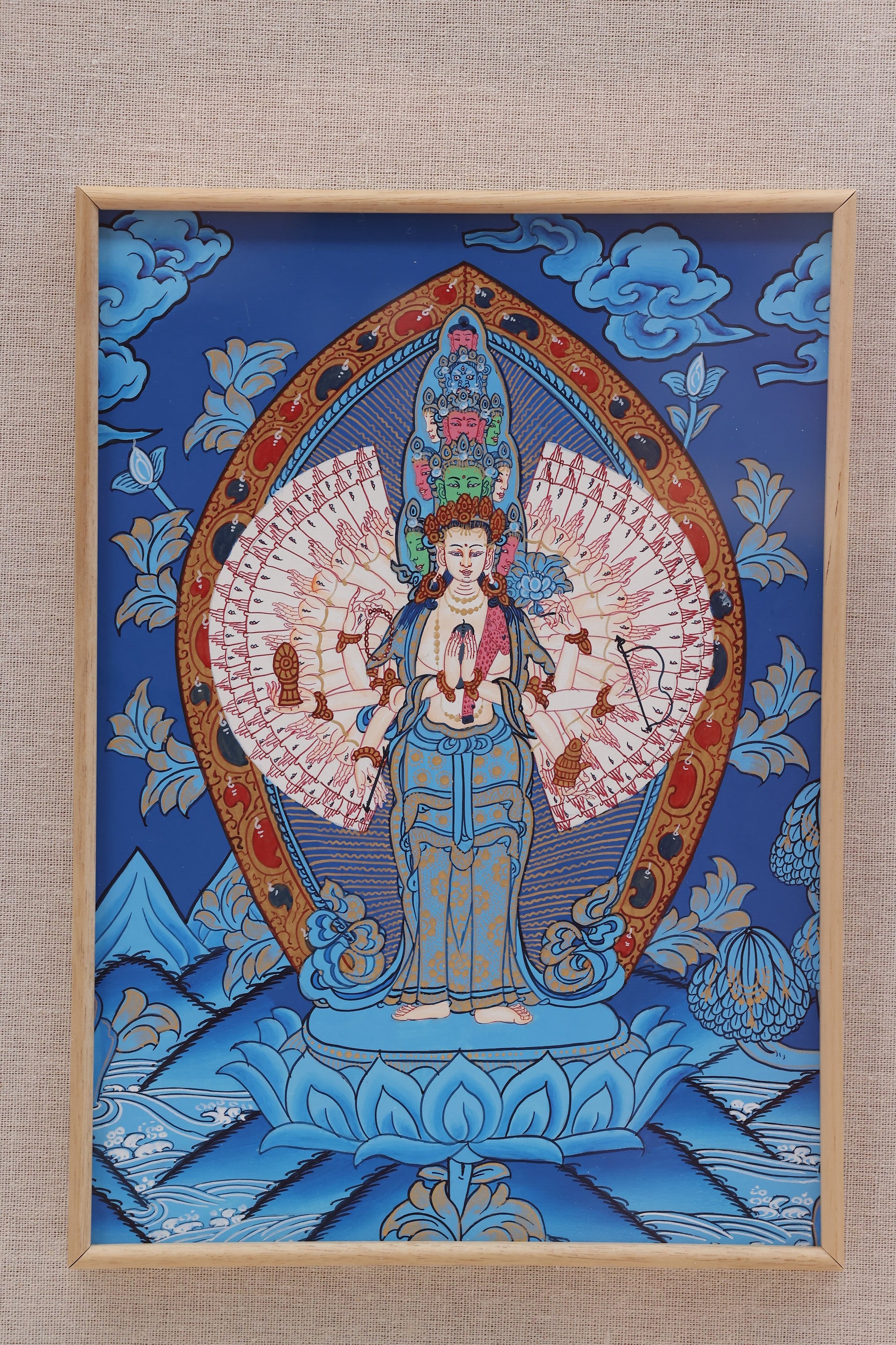 Colorful Tibetan Buddhist Thangka depicting Eleven-Faced Avalokiteshvara, surrounded by attendant deities and auspicious clouds.