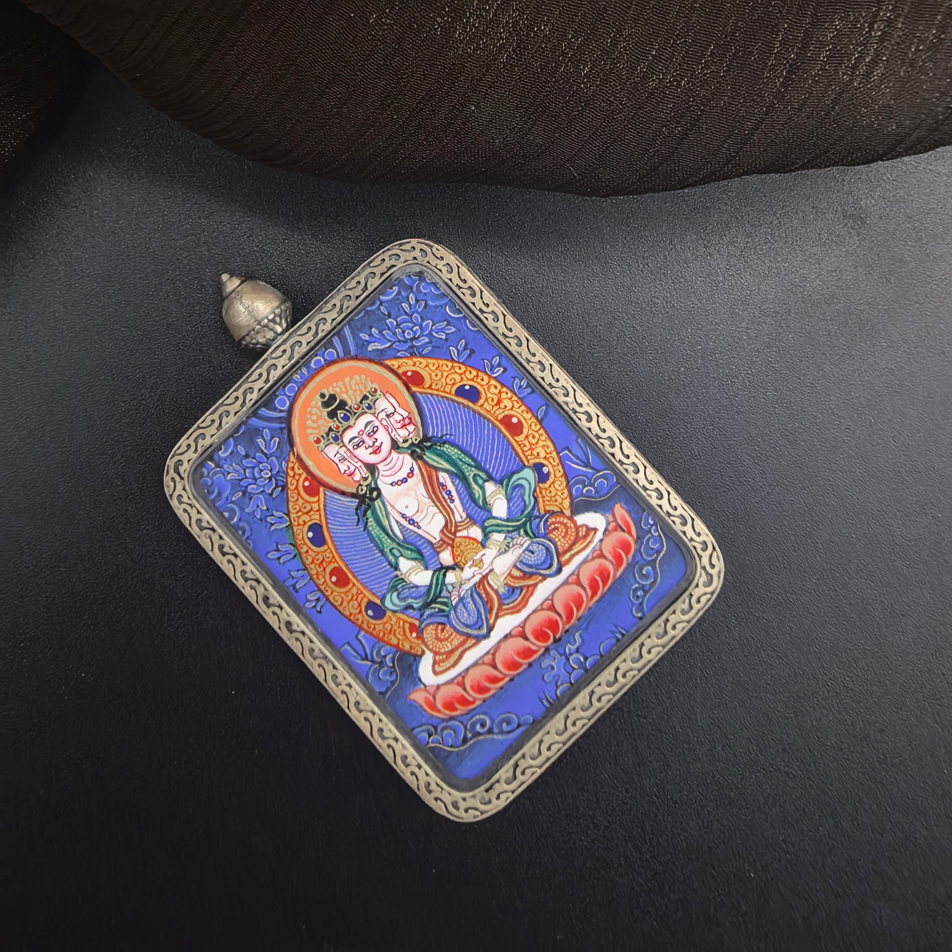 A 3.5x4.5cm hand-painted Rekong Blue Thangka Vairocana (大日如来) Thangka pendant with 925 silver featuring the Buddha of luminous wisdom, representing light and success in Buddhist tradition.
