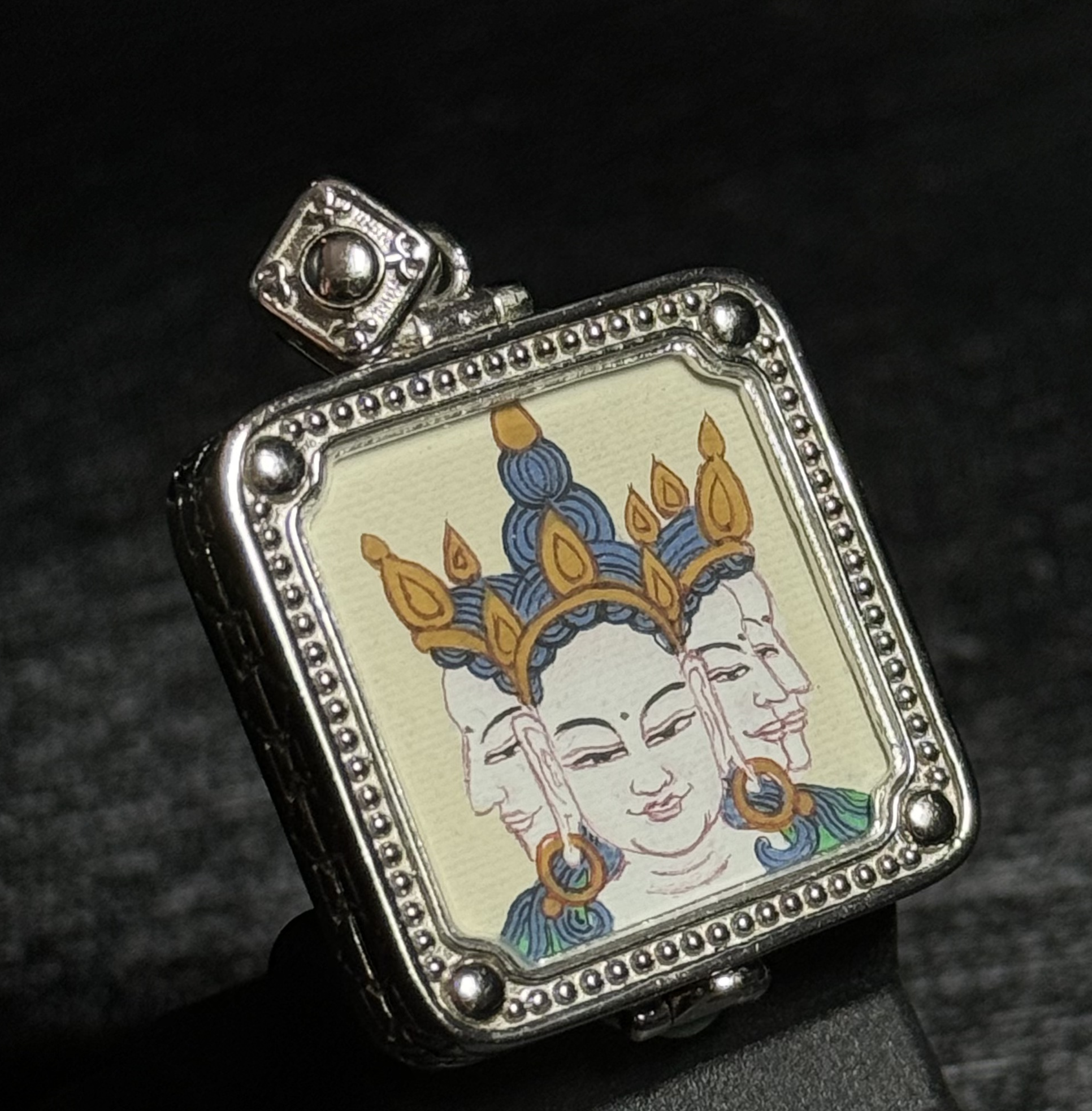 A 2x2cm hand-painted Tibet Vairocana (Great Sun Buddha) Thangka pendant featuring the symbol of light and wisdom, representing success and noble support in Buddhist tradition.
