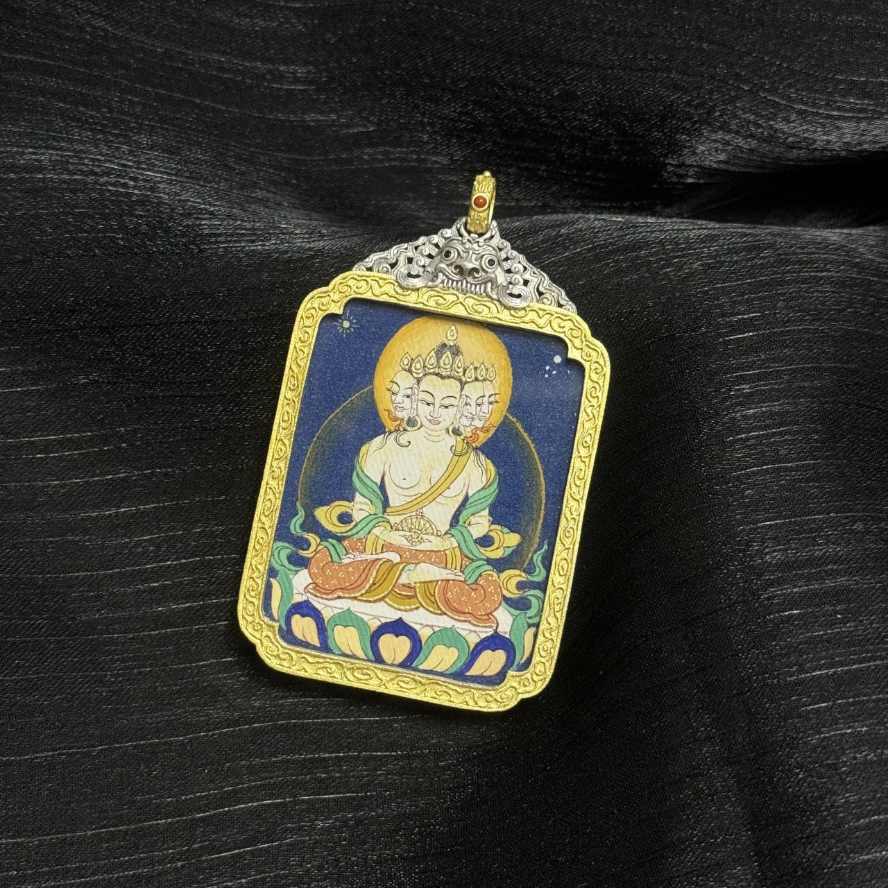  A 3.5x4.5cm hand-painted Bold-style Vairochana Buddha Thangka pendant featuring the Buddha of Cosmic Light, encased in silver-tone metal, symbolising wisdom and success in Tibetan Buddhist tradition.
