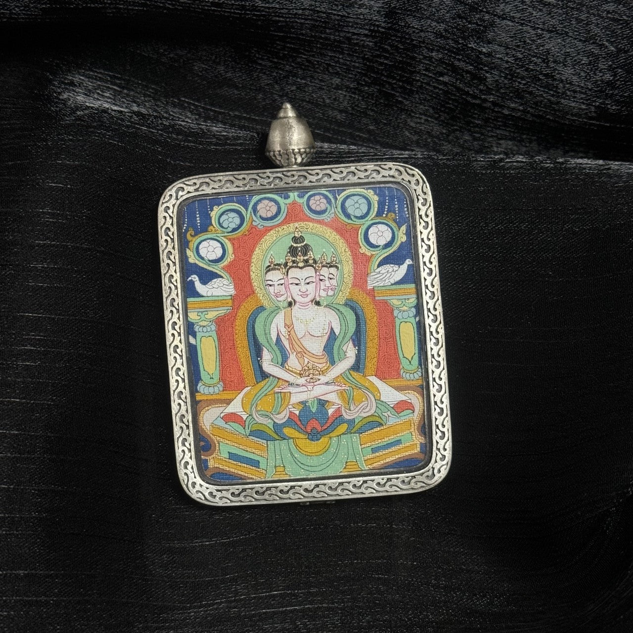  A 4x5cm hand-painted Chigung-style Vairochana Buddha Thangka pendant featuring the Buddha of Cosmic Light, encased in 925 silver with Dunhuang Nine-Colour Deer design, symbolising wisdom and success in Tibetan Buddhist tradition.
