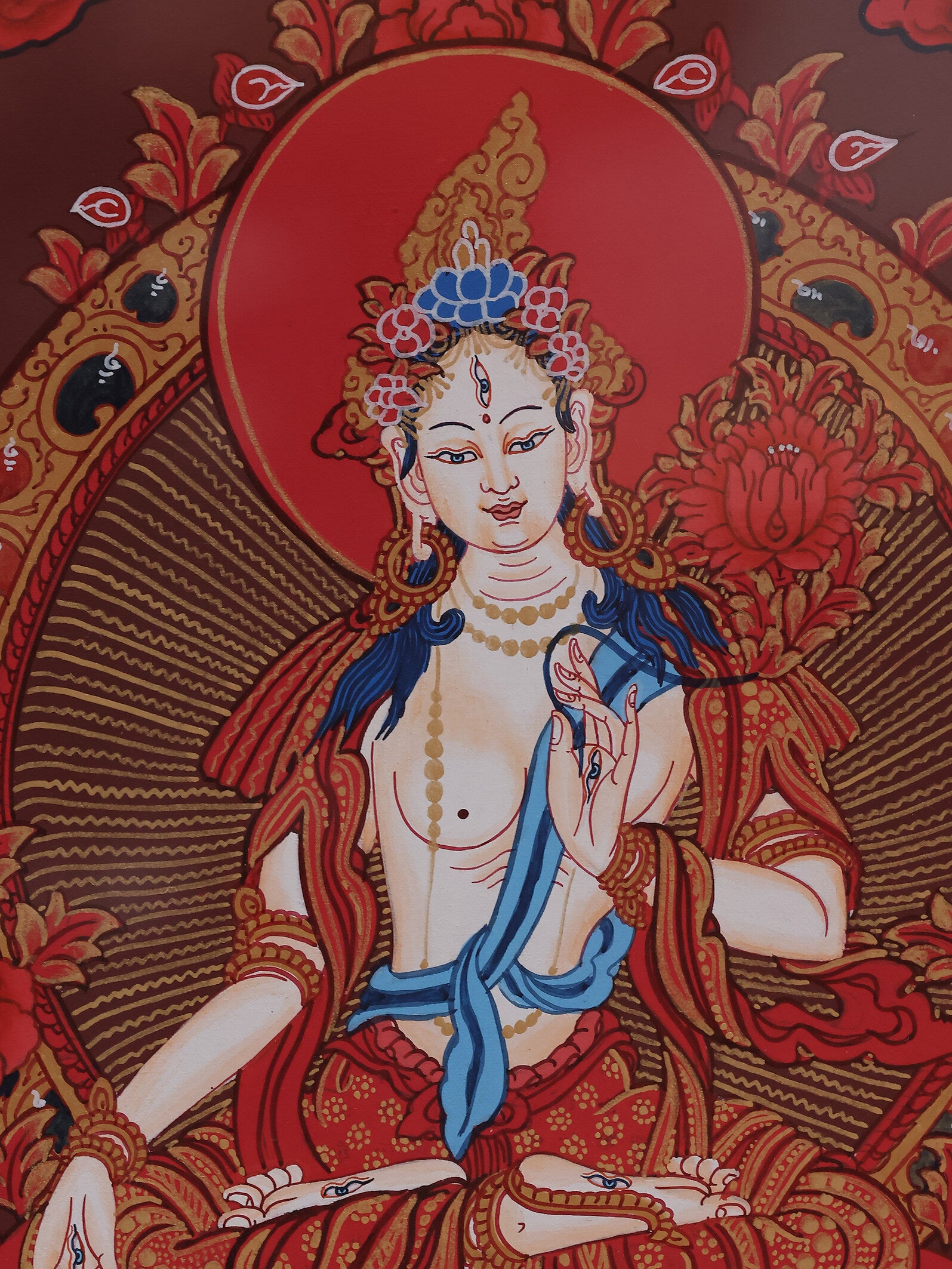 White Tara with seven eyes portrayed in a red thangka, symbolizing awareness, compassion, and long life