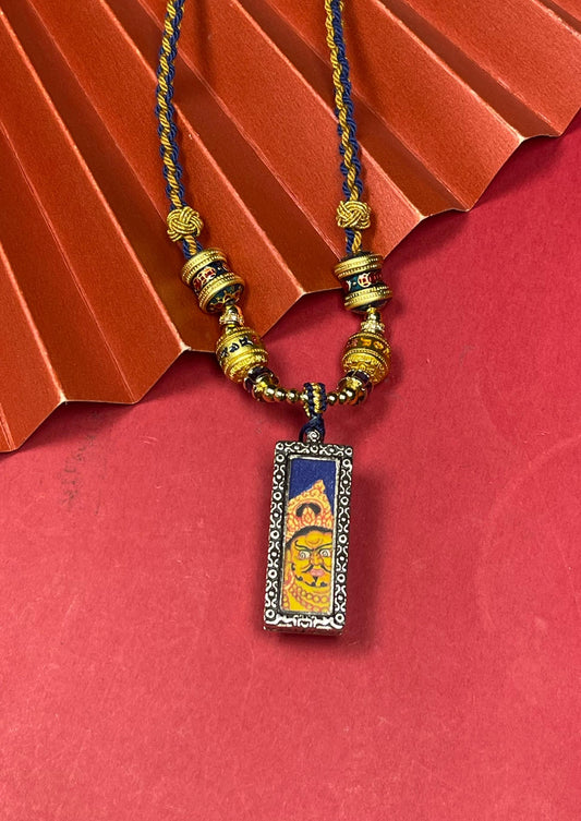 Hand-painted Nepal Blue Base Bold Yellow Jambhala (蓝底粗矿黄财神) Thangka pendant 1x3 inch with silver copper casing featuring the chief of wealth deities, representing prosperity in Buddhist tradition.
