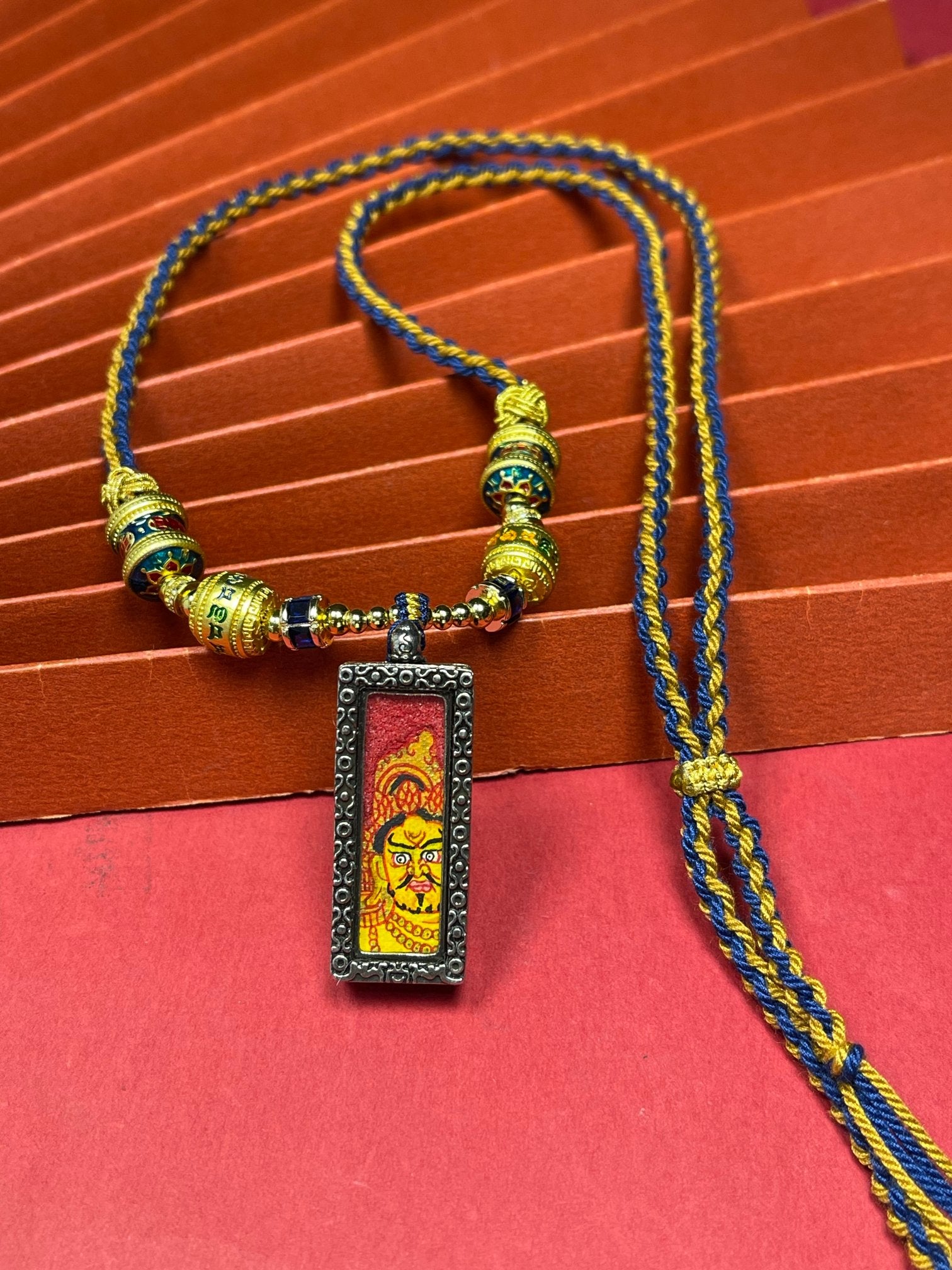 Hand-painted Nepal Red Base Bold Yellow Jambhala (红底粗矿黄财神) Thangka pendant 1x3 inch with silver copper casing featuring the chief of wealth deities, representing prosperity in Buddhist tradition.
