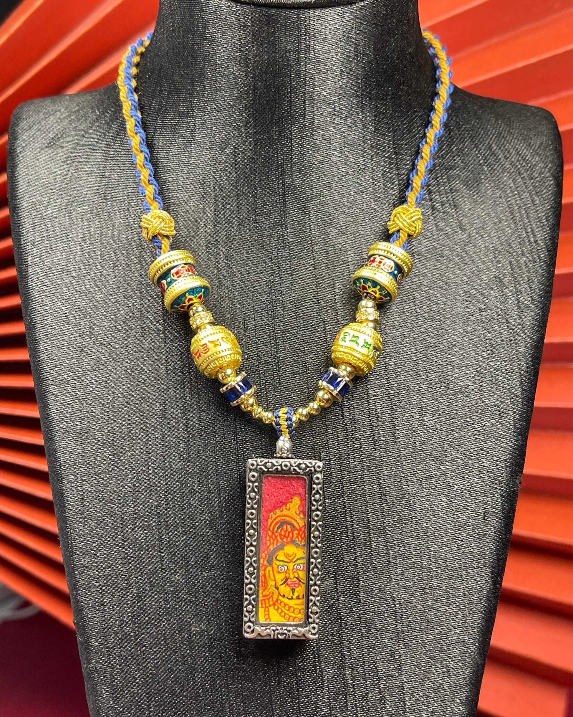 Close-up detail of the Nepal Red Base Yellow Jambhala Thangka showing hand-painted mineral pigments, showcasing the masterful artistry.
