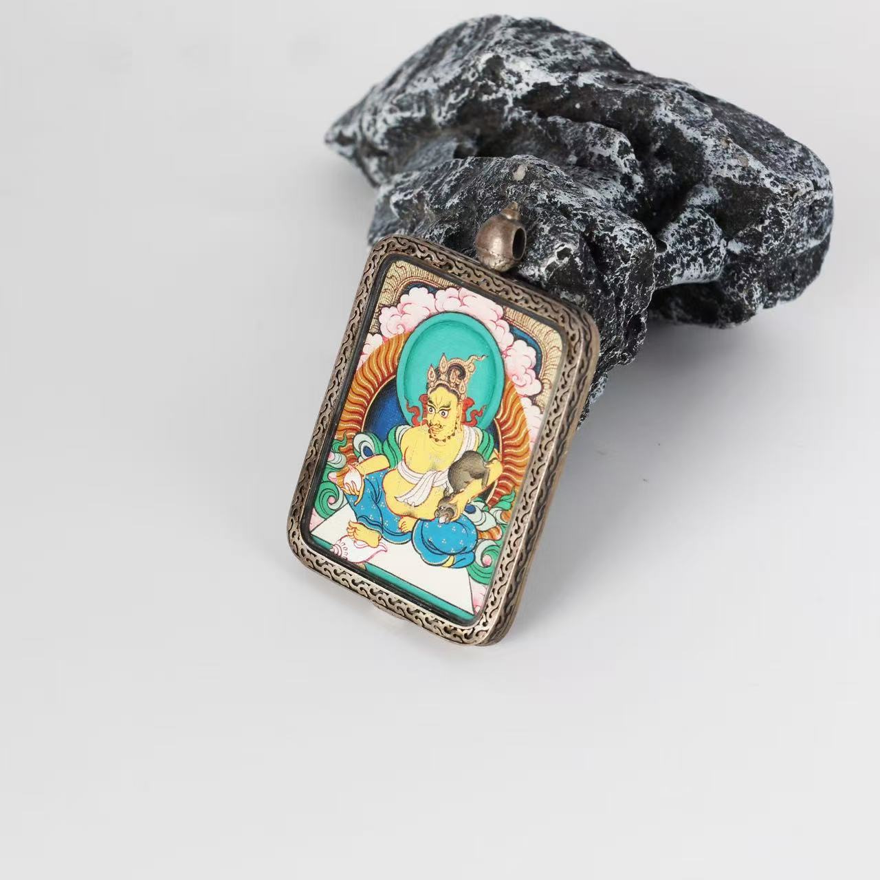  The Rebgong Yellow Jambhala Thangka pendant displayed as a sacred amulet for wealth and prosperity, embodying Tibetan Buddhist tradition.

