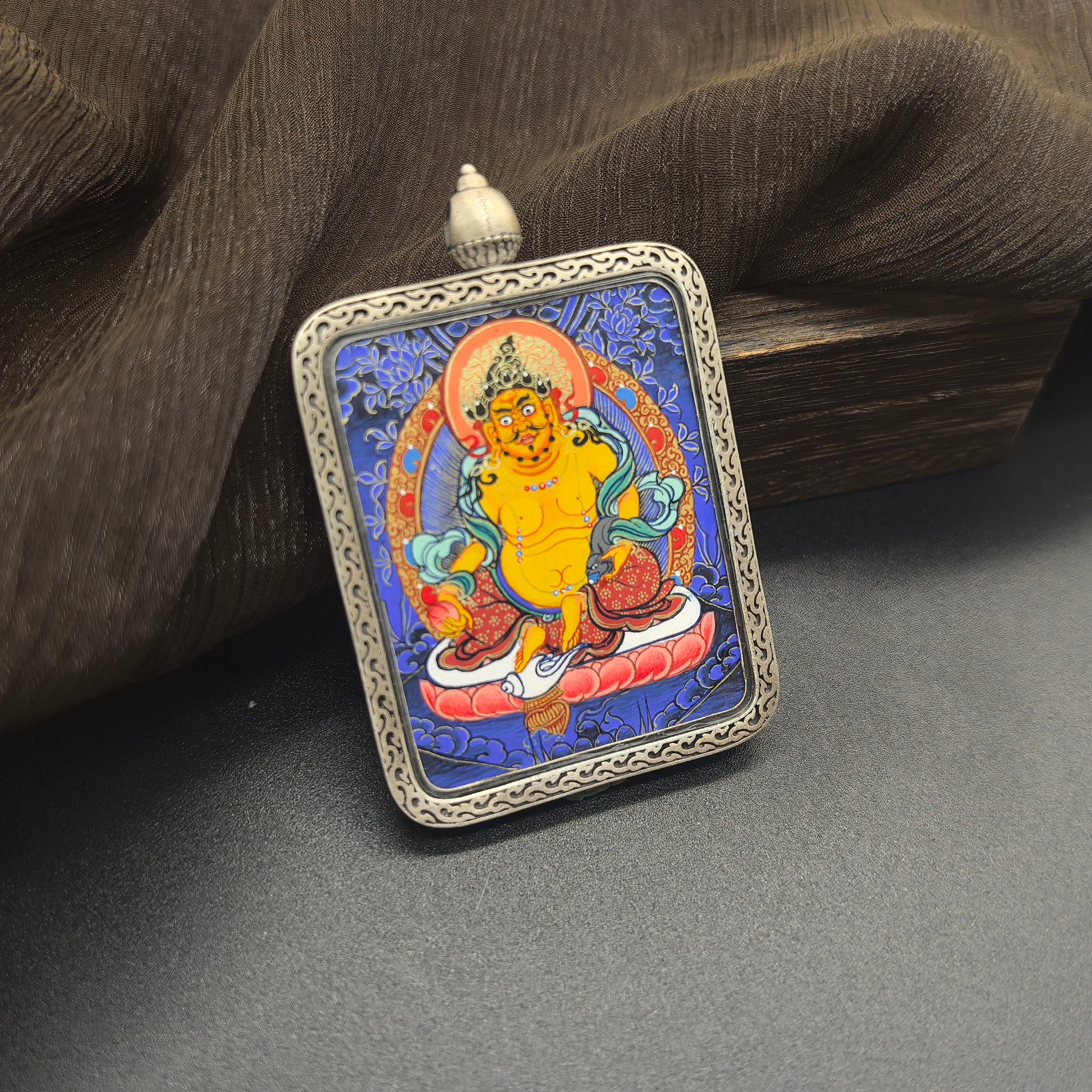 The Rekong Blue Thangka Yellow Jambhala pendant with 925 silver displayed as a sacred amulet for wealth and prosperity, embodying Buddhist tradition.

